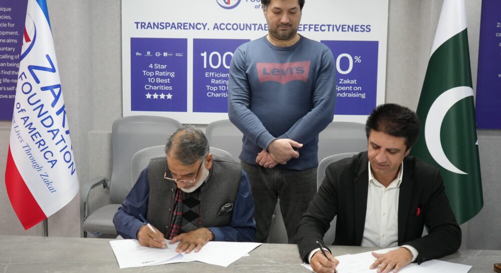 SCI and Zakat Foundation of America officials exchange documents after signing an MoU in Islamabad.