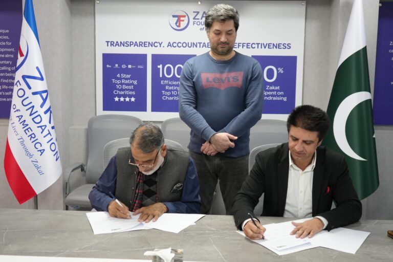 SCI and Zakat Foundation of America officials exchange documents after signing an MoU in Islamabad.